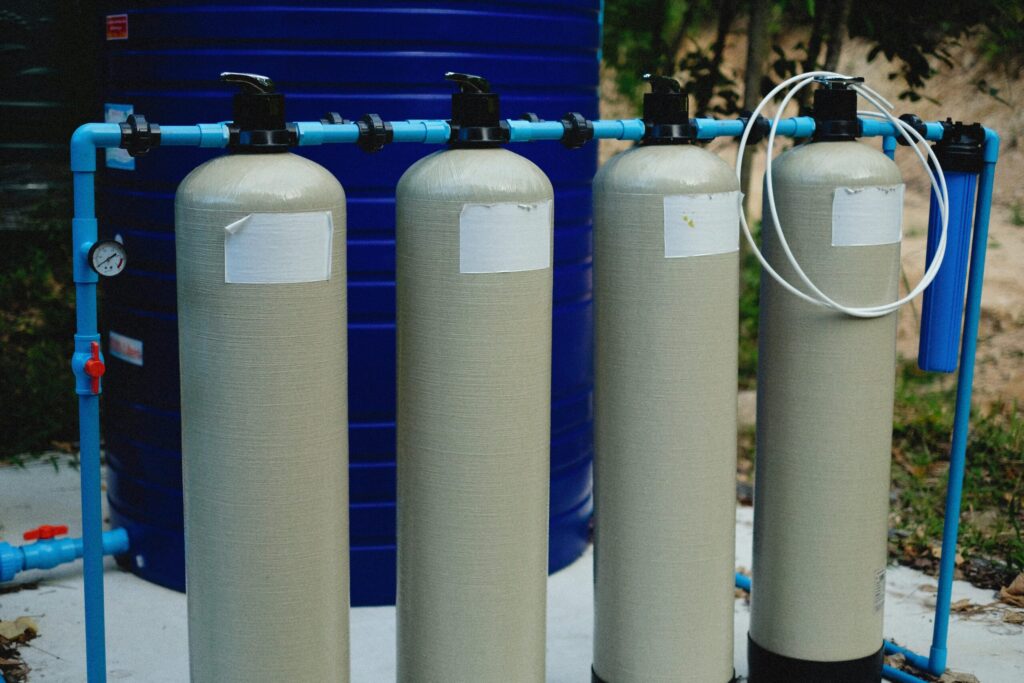 gas-pipeline Four beige tanks in an outdoor water treatment setup with blue piping.